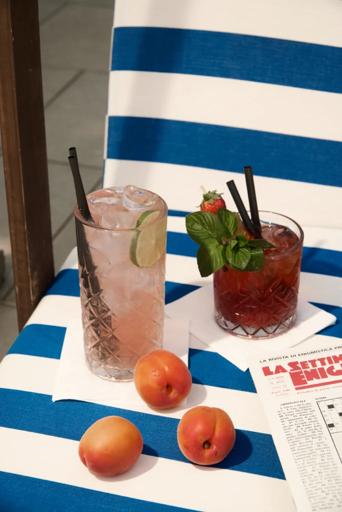 Due cocktail e albicocche su un tavolo a righe bianche e blu